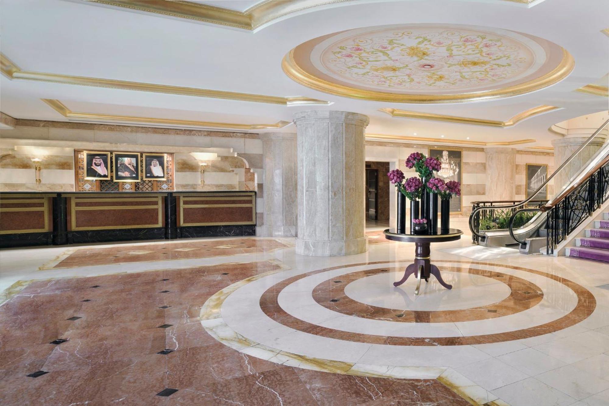 Intercontinental Dar Al Iman Madinah By Ihg Hotell Medina Exteriör bild The photo shows a luxurious hotel lobby. The space features elegant marble flooring with circular designs, complemented by a large, decorative ceiling. In the center, there is a round table adorned with a floral arrangement. Behind the table, a recep
