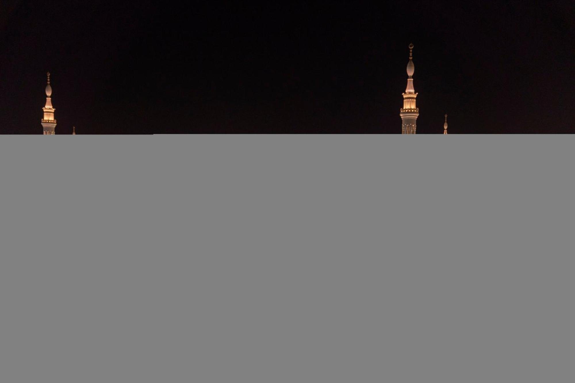 Intercontinental Dar Al Iman Madinah By Ihg Hotell Medina Exteriör bild The image appears to show a night scene featuring tall structures with pointed tops, likely minarets, illuminated against a dark background. The lighting creates a striking contrast, highlighting the architectural details of the structures. The overa