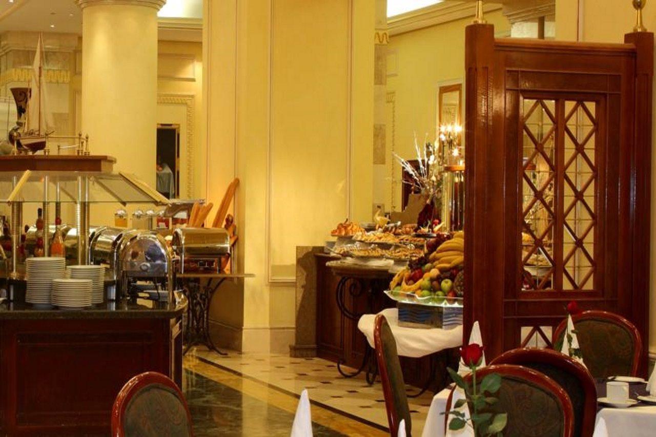 Intercontinental Dar Al Iman Madinah By Ihg Hotell Medina Exteriör bild The photo shows an elegant dining area, likely within a restaurant or a hotel. There's a buffet setup on one side with various food items displayed, including pastries and fruits. The room features warm lighting, polished floors, and decorative walls