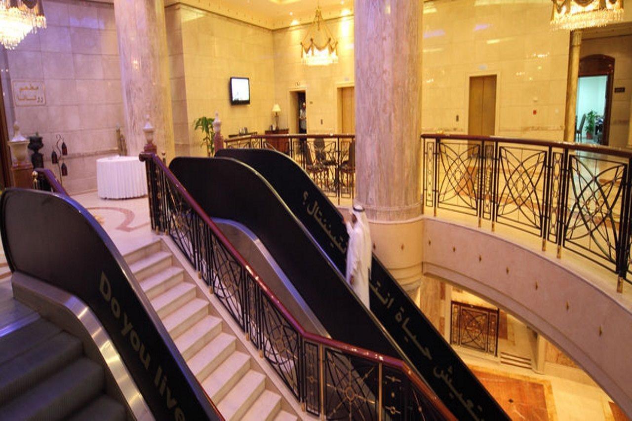 Intercontinental Dar Al Iman Madinah By Ihg Hotell Medina Inreriör bild The photo depicts an elegant interior space, likely within a hotel or a large building. There is a grand staircase visible, which features a combination of stairs and escalators. The design includes decorative railings and marble pillars, contributin